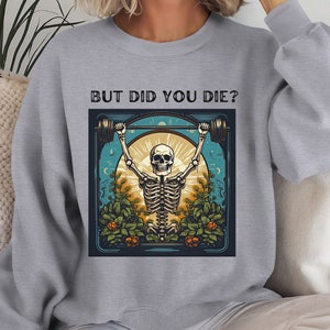 Könnte beinhalten: Grauer Pullover mit einem Aufdruck eines Skeletts, das Gewichte hebt, mit dem Text "But Did You Die?" auf der Vorderseite.