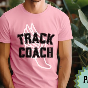 May include: A pink t-shirt with a white winged foot graphic and the text "TRACK COACH" in black.