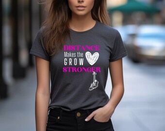 May include: A dark gray t-shirt with a white graphic that says "DISTANCE Makes the HEART GROW STRONGER" with a pink heart and a white drawing of a shoe.