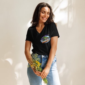 Puede incluir: Una camiseta negra con cuello en V que presenta un gráfico en el área del pecho izquierdo. El gráfico muestra un tiburón de dibujos animados verde con una caña de pescar, rodeado de salpicaduras de agua azul y el texto BBX en blanco y naranja.