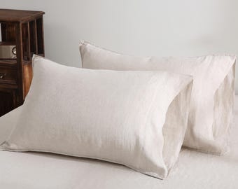 May include: Two light beige pillowcases made of linen fabric. The pillowcases are rectangular and have a soft, textured appearance. They are placed on a bed with matching sheets, creating a cohesive and neutral-toned bedding set.