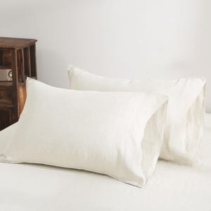 May include: Two white linen pillowcases, one on top of the other, with a slightly textured surface.