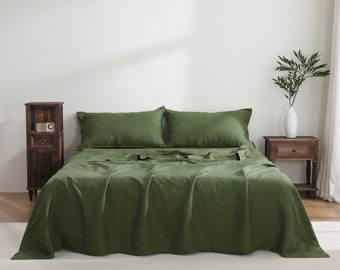 Puede incluir: Un juego de cama de lino verde con dos fundas de almohada y una funda nórdica. La ropa de cama está en una cama con una mesita de noche de madera y un jarrón con hojas verdes.