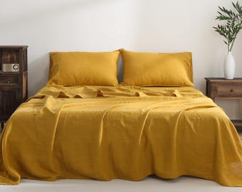 Puede incluir: Un juego de sábanas de lino de color amarillo mostaza con dos fundas de almohada a juego. La cama está hecha con el juego de sábanas y la tela tiene una textura ligeramente arrugada.