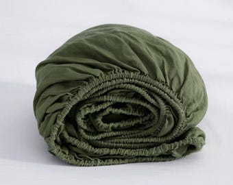 May include: A green fitted sheet is rolled up, showing the elastic edge.