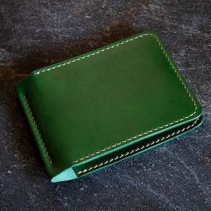 May include: A green leather wallet with a stitched edge.