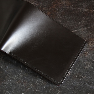 May include: A black leather wallet with a stitched edge.
