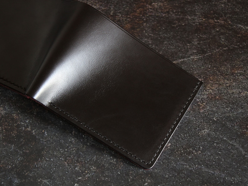 May include: A black leather wallet with a stitched edge.
