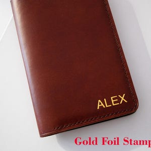 May include: A brown leather notebook with gold foil stamping that reads "ALEX".