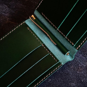 May include: A dark green leather wallet with a money clip and multiple card slots.