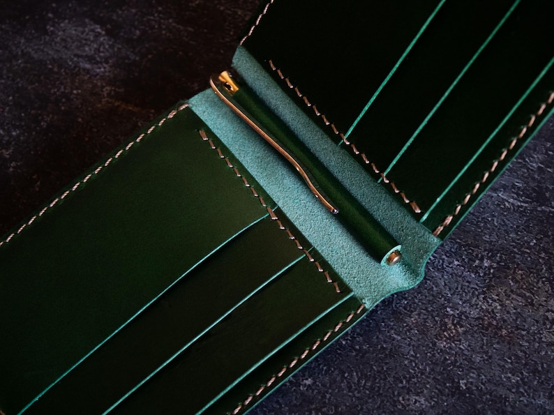 May include: A dark green leather wallet with a money clip and multiple card slots.