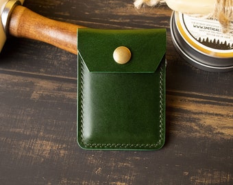 Puede incluir: Un porta tarjetas de cuero verde oscuro con un borde cosido y un cierre de botón de latón.