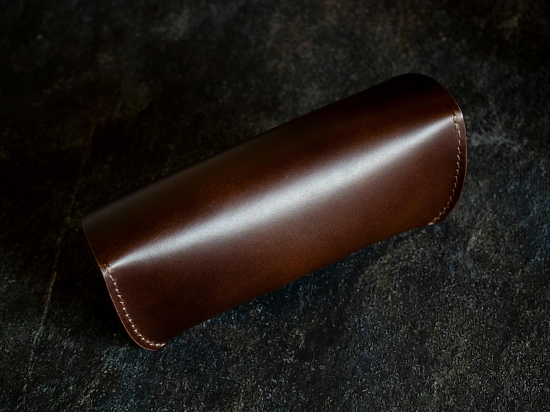 May include: A brown leather case with a stitched edge.