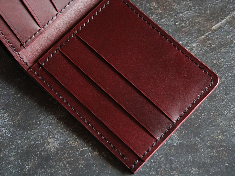 May include: A burgundy leather wallet with black stitching and multiple card slots.
