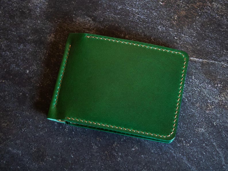 May include: A green leather wallet with a stitched edge.