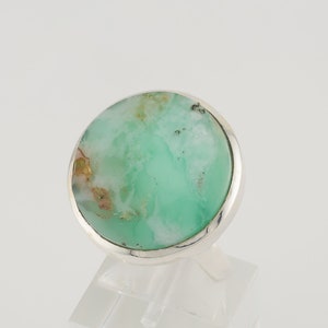 May include: A silver ring with a green and white gemstone. The gemstone is round and has a smooth surface.