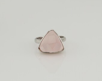 Puede incluir: Un anillo de plata con una gran gema triangular de color rosa pálido. La gema facetada captura la luz. El anillo tiene un diseño simple y elegante, adecuado para el uso diario o para ocasiones especiales.
