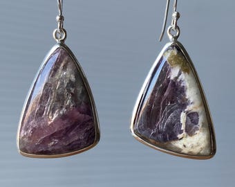 May include: A pair of silver dangle earrings with a triangular shaped purple and white gemstone.