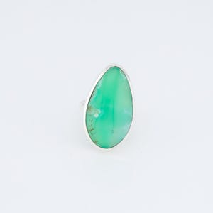 May include: A silver ring with a green gemstone in a teardrop shape.