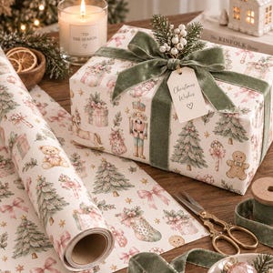 May include: A rectangular gift box wrapped in white paper featuring illustrations of nutcrackers, teddy bears, Christmas trees, and bows. The box is tied with a sage green velvet ribbon, a sprig of white berries, and a tag reading Christmas Wishes.