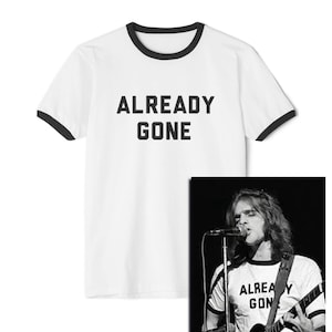 May include: White t-shirt with black ringer and the text "ALREADY GONE" printed in black. A black and white photo of a person wearing a similar t-shirt and playing a guitar is shown in the background.