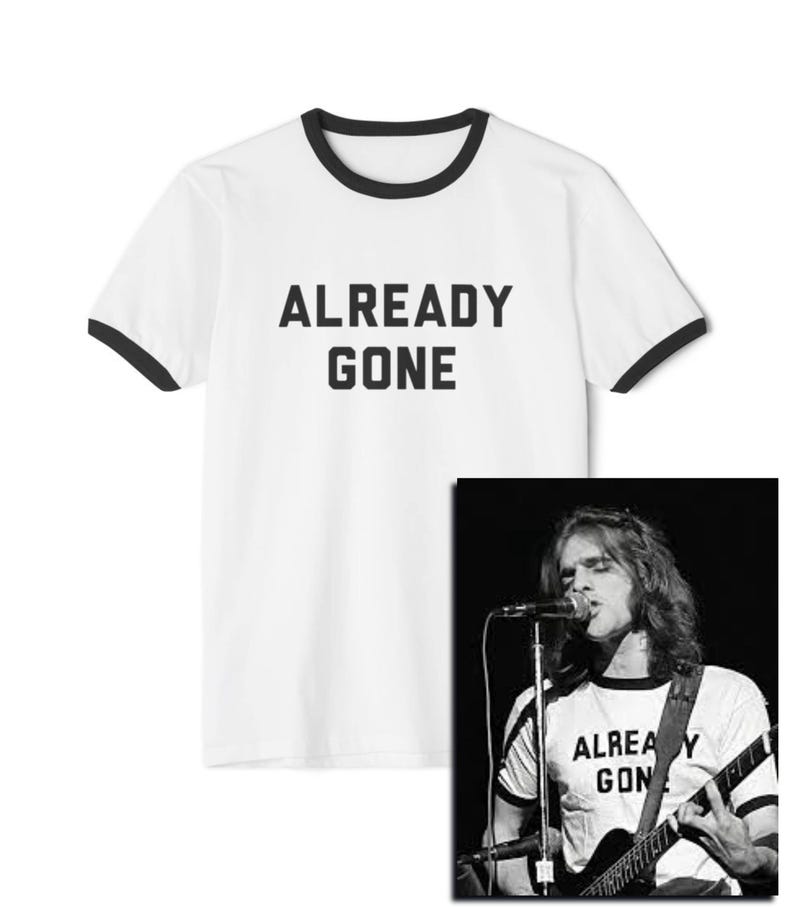 May include: White t-shirt with black ringer and the text "ALREADY GONE" printed in black. A black and white photo of a person wearing a similar t-shirt and playing a guitar is shown in the background.
