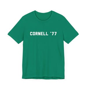 May include: A green t-shirt with white text that reads "CORNELL '77".