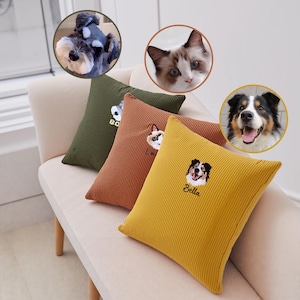 May include: Four corduroy throw pillows in olive green, rust, and yellow, each embroidered with a pet's face and name. The pillows are square and have a ribbed texture. The background includes a light-colored sofa and three pet portraits.