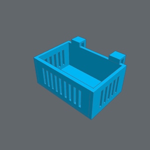 Puede incluir: Una cesta de almacenamiento de plástico azul claro con forma rectangular y lados abiertos. La cesta tiene una serie de ranuras verticales en la parte delantera y los lados.