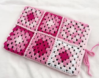 May include: Pink and white crocheted granny square laptop sleeve with a drawstring closure.