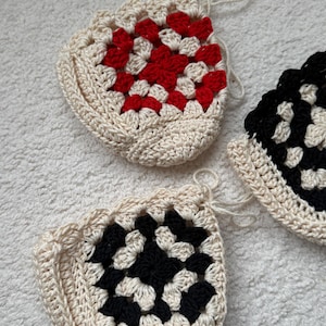 May include: Three crocheted granny square pouches in different color combinations. One pouch is white with red squares, one is white with black squares, and one is black and white.