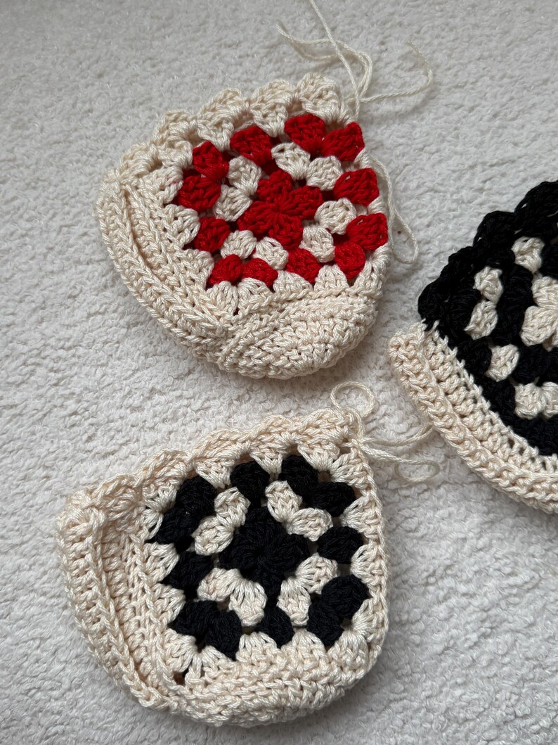 May include: Three crocheted granny square pouches in different color combinations. One pouch is white with red squares, one is white with black squares, and one is black and white.