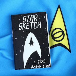 May include: A black and white sketchbook with the text "STAR SKETCH a TOS sketch zine" and a white Star Trek insignia on the cover.