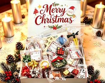 May include: A white cardboard gift box with the text Merry Christmas printed on the inside lid. The box is filled with various small items in clear plastic bags, including colorful bows, a miniature Rubik's cube, and small holiday ornaments.