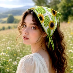 May include: A triangular crochet headscarf featuring a repeating pattern of green and white squares with yellow and brown sunflower motifs. The headscarf is tied at the back with two thin green crochet strings, creating a textured and colourful accessory.