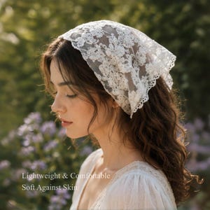 May include: A white lace headscarf with floral patterns. The head covering is lightweight and comfortable, as indicated by the text in the image. The scarf is worn on the head and drapes over the hair.