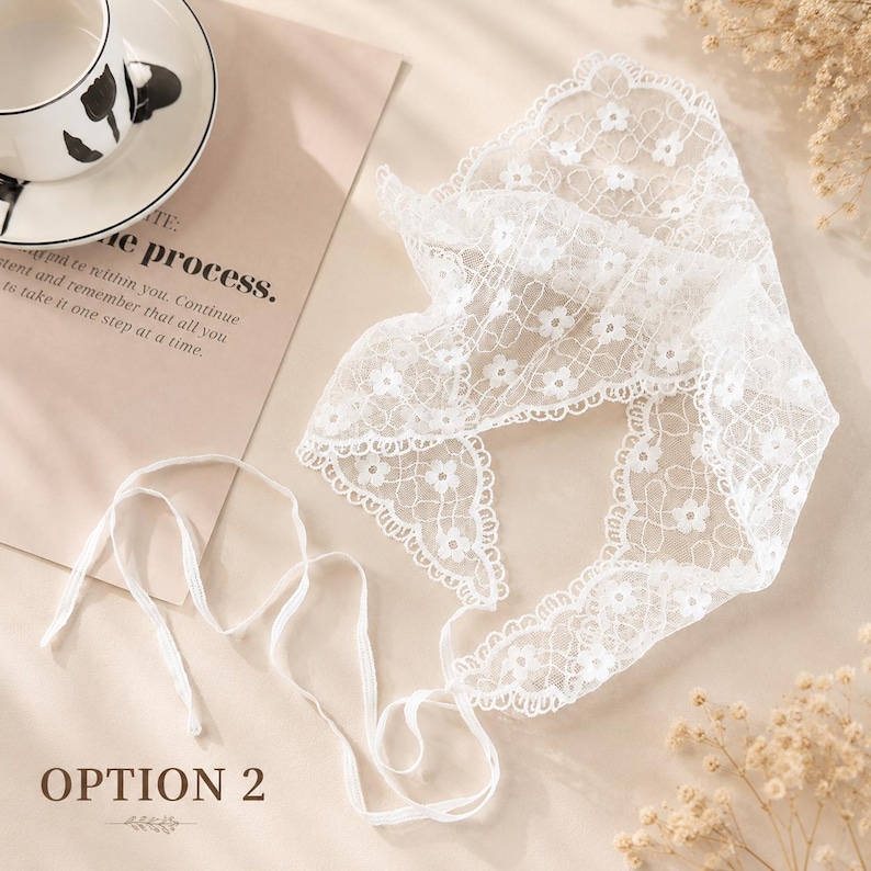 May include: A delicate white lace head covering with floral patterns and a scalloped edge. The head covering has long, thin ties. The text "OPTION 2" is visible in the image.
