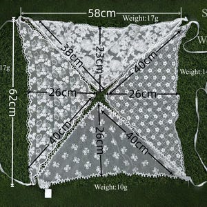 May include: White lace shawl with floral patterns, measuring 62cm in length and 58cm wide. The shawl is composed of four triangular sections, each with a 40cm side. The weight of the shawl is 17g, 17g, 14g and 10g.