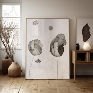 Puede incluir: Una impresión de arte abstracto en blanco y negro de flores estilizadas con líneas finas. La impresión está enmarcada en un marco de madera claro y está colgada en una pared blanca.