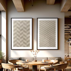 Può includere: Un tavolo da pranzo rotondo in legno con quattro sedie in un ambiente da caffè moderno. Il tavolo è rotondo e ha una finitura in legno chiaro. Le sedie sono anch'esse in legno e hanno una finitura marrone scuro. Ci sono due stampe incorniciate sul muro dietro il tavolo. Entrambe le stampe sono astratte e presentano motivi geometrici in tonalità di grigio.