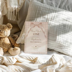 May include: A pink and white gingham patterned invitation with a pink bow and the text "Beautiful One" and "Sophia's First Birthday".