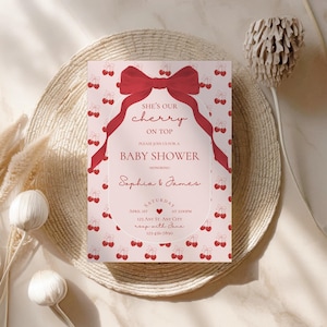 May include: A pink baby shower invitation with a red bow and cherries. The text reads "She's our cherry on top. Please join us for a baby shower honoring Sophia & James. Saturday, April 1st at 2:00pm. 123 Any St. Any City. RSVP with Jane 123-456-7890."
