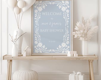 May include: A light blue baby shower sign with a white floral border. The sign says "Welcome to Mia & James Baby Shower 10.24.XX".