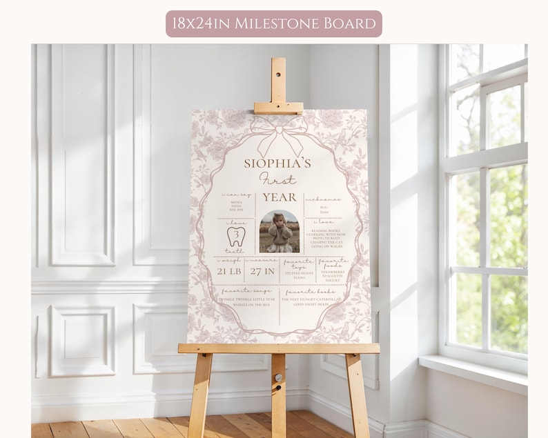 May include: A pink and white milestone board with a floral design and a photo of a baby girl. The board includes information about the baby's first year, including their weight, height, and first tooth. The text on the board reads "Sophia's First Year".