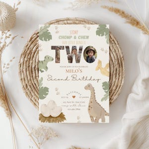 May include: A dinosaur-themed birthday invitation with a photo of a child in a safari hat. The invitation says "Stomp, Chomp & Chew, Our Little Dino is Two, Please Join Us to Celebrate Milo's Second Birthday, Saturday, July 24, at 4:00 PM, 123 Any St. Any City, RSVP with Jane, 123-456-7890."