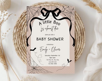 Puede incluir: Una invitación a una fiesta de bienvenida al bebé de color rosa y blanco con telarañas negras, murciélagos y un lazo negro. El texto dice "A little Boo is almost due. Join us for a baby shower honoring Emily + Oliver. Saturday September 1st, 4pm-6pm, 123 Any St. Any City, rsvp with Jane, 123-456-7890."