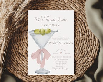 May include: A white baby shower invitation featuring a martini glass illustration with a pink ribbon. The text reads "A Tini One Is On Way" and includes the name "Penny Anderson".