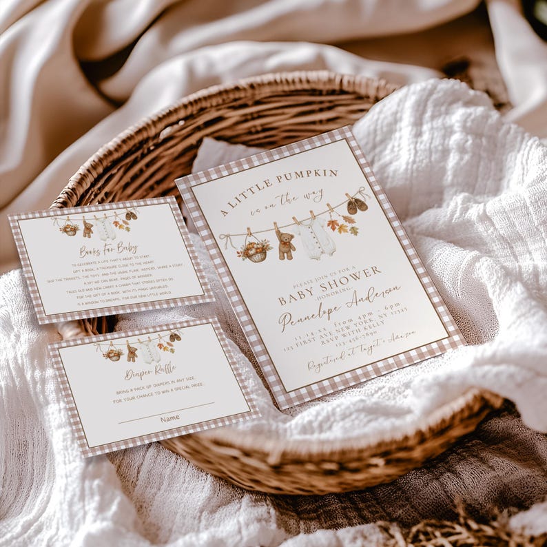 May include: A set of three rectangular baby shower invitation cards with a brown and white gingham border. The cards feature illustrations of a clothesline with a teddy bear, baby clothes, and autumn leaves, with text including A Little Pumpkin.