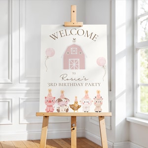 May include: A wooden easel displays a party sign with the word "WELCOME" above a pink barn illustration. The sign welcomes guests to "Rosie's 3rd Birthday Party" and features cartoon farm animals and balloons.
