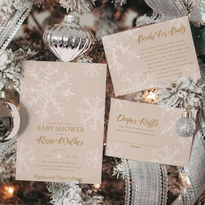 May include: Baby shower invitations and inserts with snowflake designs in gold and white on a light tan background. The invitations include the text "Baby Shower" and "Rosie Walker". The inserts include "Books For Baby" and "Diaper Raffle".